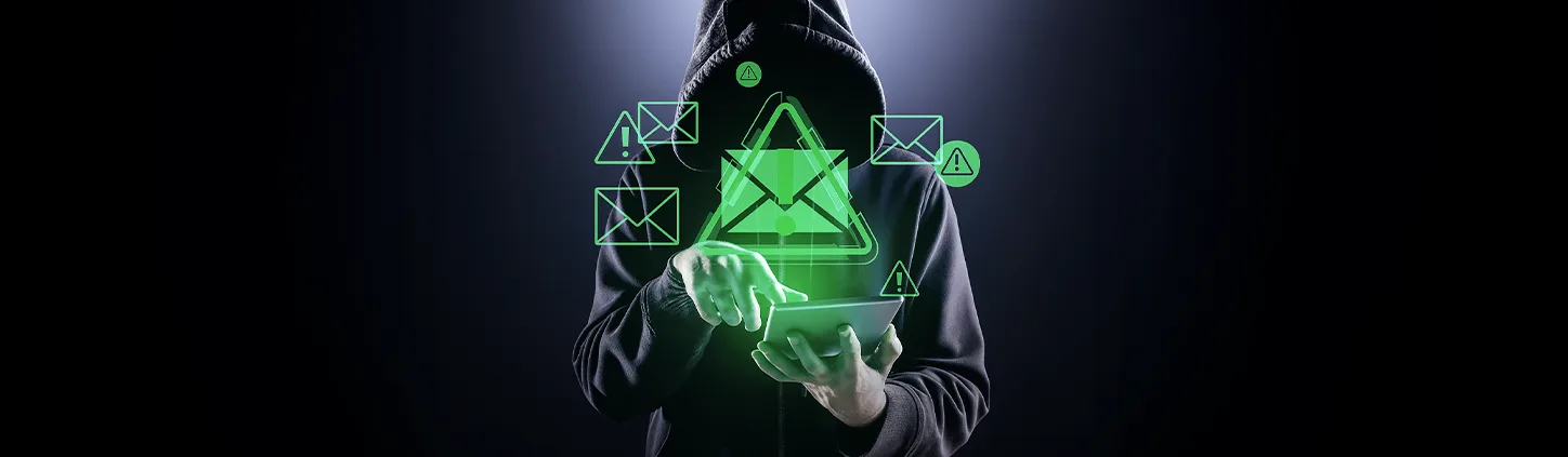 Uma pessoa encapuzada e com o rosto oculto manipula um tablet que exibe ícones digitais de e-mails e alertas de perigo em verde. A imagem simboliza a ameaça da engenharia social, onde criminosos usam a manipulação para obter acesso a informações confidenciais.