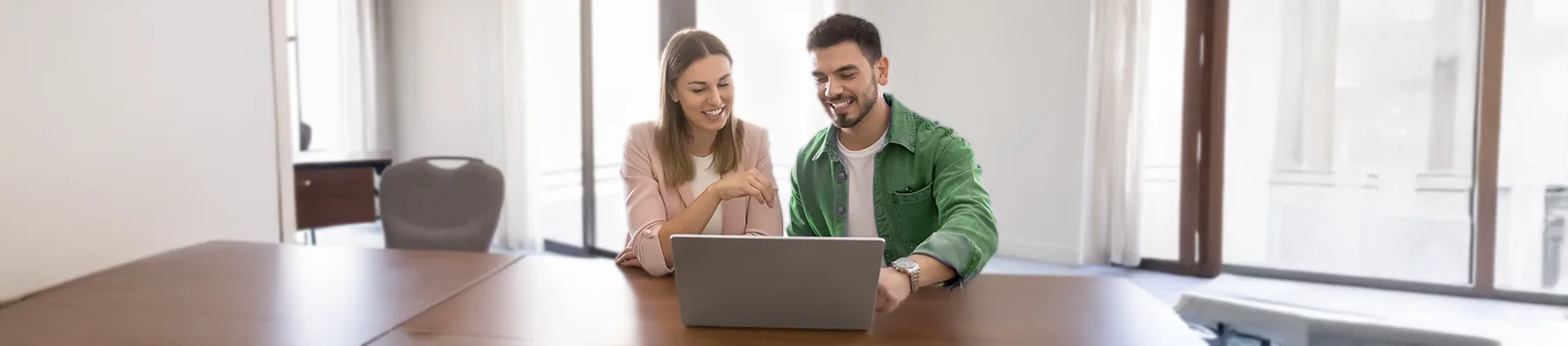 Sócios usam laptop para definir o orçamento anual empresarial e alinhar estratégias financeiras.