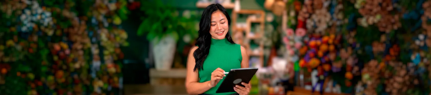 Empreendedora utiliza tablet em uma floricultura, mostrando a praticidade da assinatura digital para pequenas empresas no dia a dia do negócio.